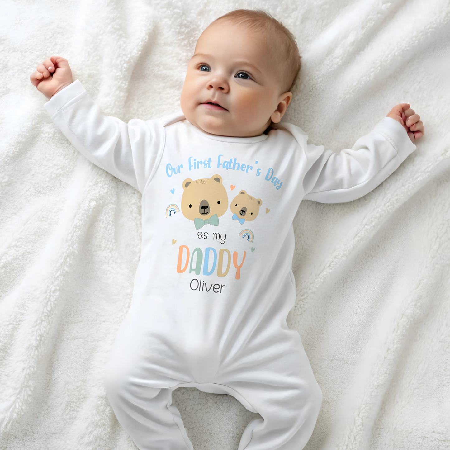 First Father's Day Outfit: A baby dressed in a personalized First Father’s Day outfit. This unique gift for new dads includes a choice of a sleepsuit, vest, T-shirt, or bib, all featuring a charming design. At the top, it reads “First Father’s Day as My Daddy,” accompanied by an adorable illustration of a baby bear and a father bear, along with the child’s name.