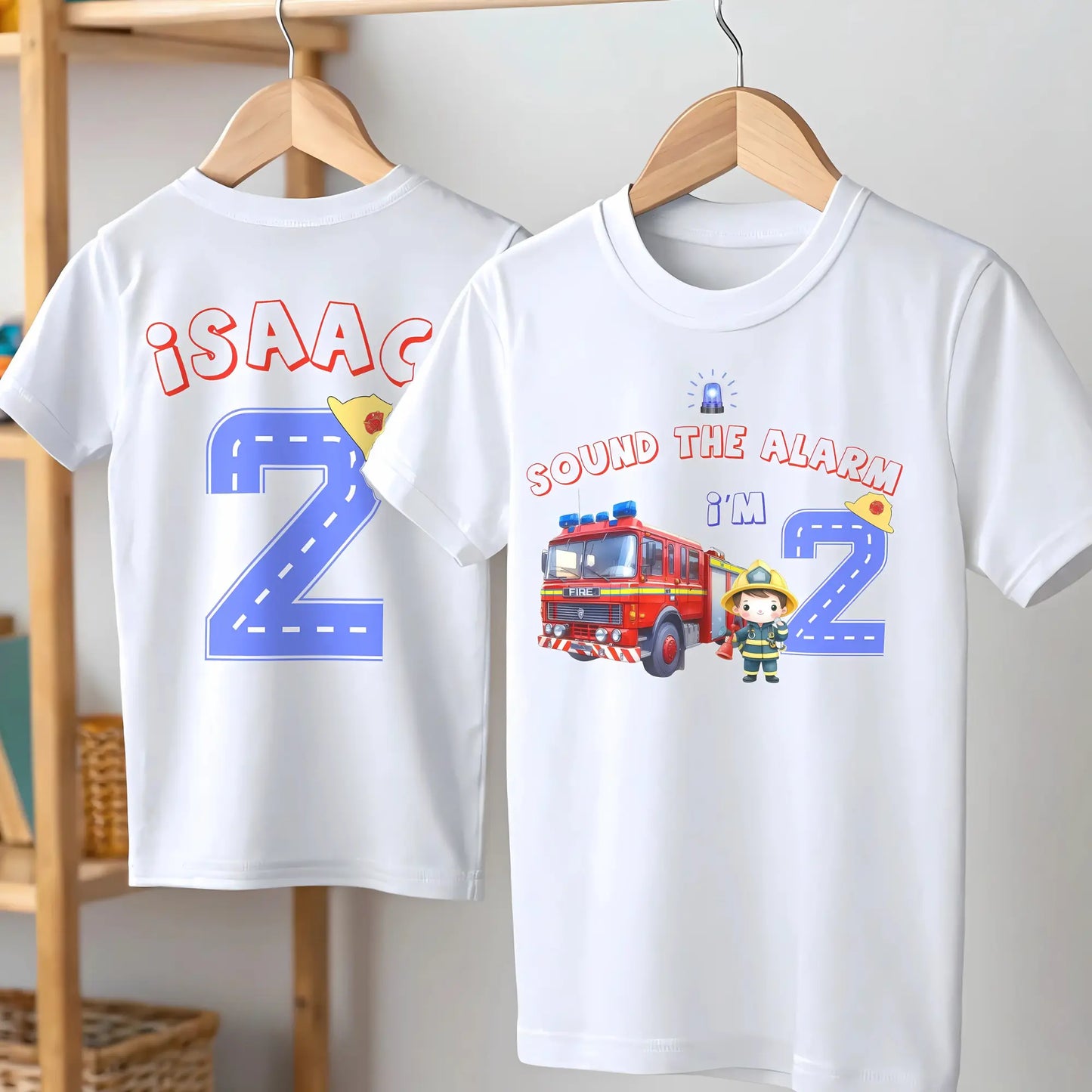 Personalised Fire Engine Birthday T-Shirt: A customizable white birthday shirt featuring a red fire truck and firefighter. The top reads “Sound the Alarm I'm” followed by your choice of age number. The back displays the toddler's name and a blue number adorned with a firefighter hat. An ideal gift for firefighter-themed birthday parties for toddlers.