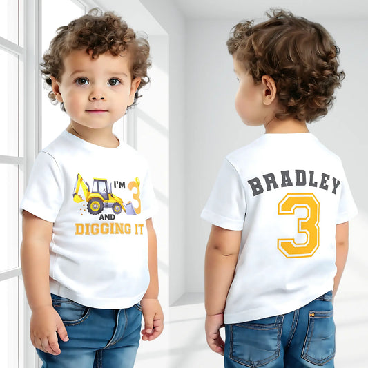 Excavator Digger Birthday T-Shirt: This white t-shirt features a vibrant yellow excavator graphic alongside the playful text “I am digging it,” with customizable age options to celebrate a birthday. The back is personalised with the boy name and age in bold yellow with a black outline. Ideal as a gift for a boy or toddler birthday or a construction-themed party.