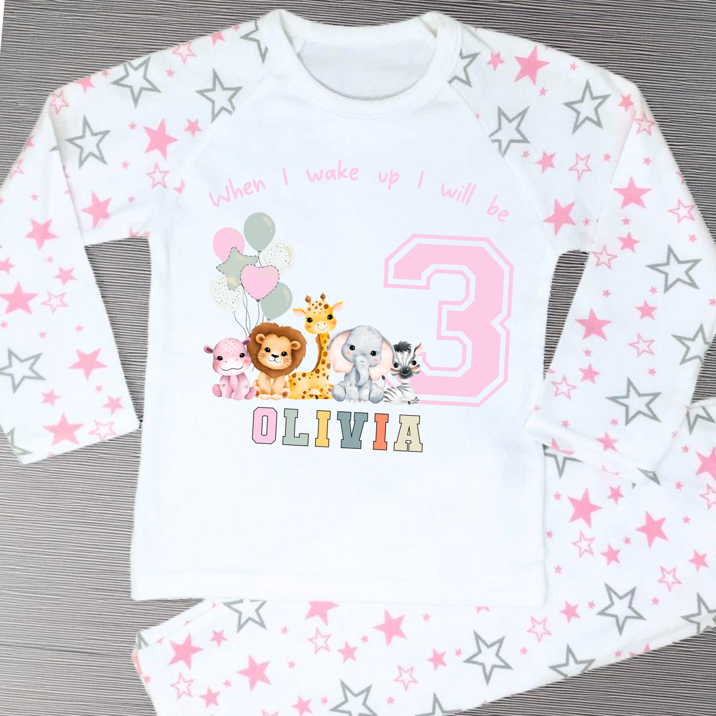 safari birthday pyjamas, A personalised set of girls birthday pyjamas in pink. At the top it says when i wake up i will be followed by some safari jungle animals holding some birthday balloons. They are sat beside a number that represents the child age on birthday. Under that is the child name in safari rainbow colours. This is perfect gift for a toddler first birthday.
