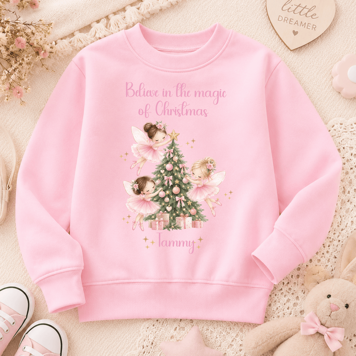 Personalised Christmas sweatshirt for girls featuring magical pink fairies decorating a Christmas tree, customised with the child’s name.