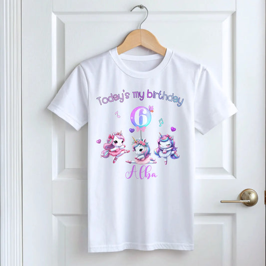 A pastel pink and lilac unicorn birthday T-shirt for girls and toddlers, featuring a cute unicorn design. Made from soft, breathable 100% cotton, this shirt offers both style and comfort. It can be personalised with a name, making it a unique birthday gift for girls. Perfect for a little dancer's birthday celebration, combining magic and comfort as she twirls and plays. Unicorn birthday gift, personalised unicorn, custom name tshirt