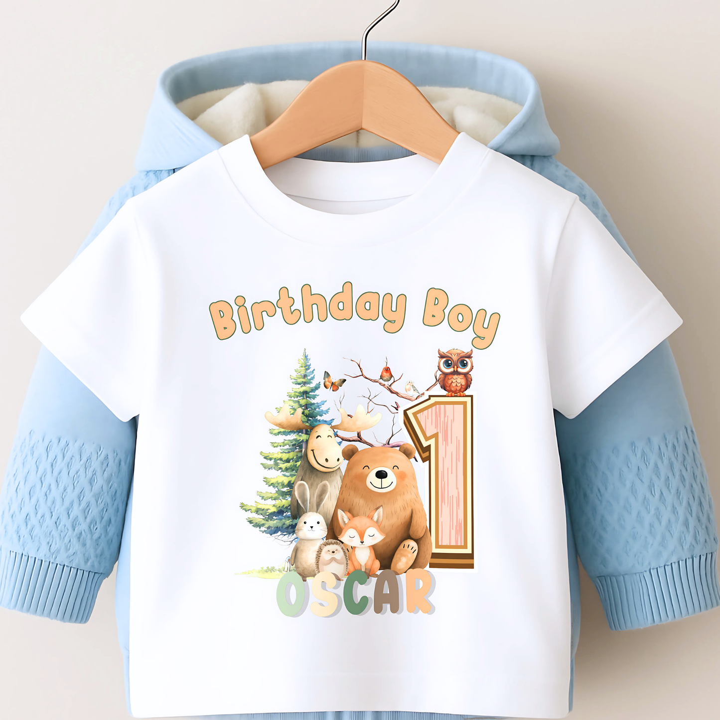 Woodland animal birthday t-shirt: A children's birthday t-shirt featuring a woodland animal theme. The shirt displays a forest scene with a playful fox, a curious bear, and a gentle bear, surrounded by lush greenery. The design uses earthy tones and vibrant greens to create a natural look. At the top, the words “Birthday Boy” are printed, with space for a personalized name underneath. Made from soft, high-quality fabric, it’s designed for comfort and durability.