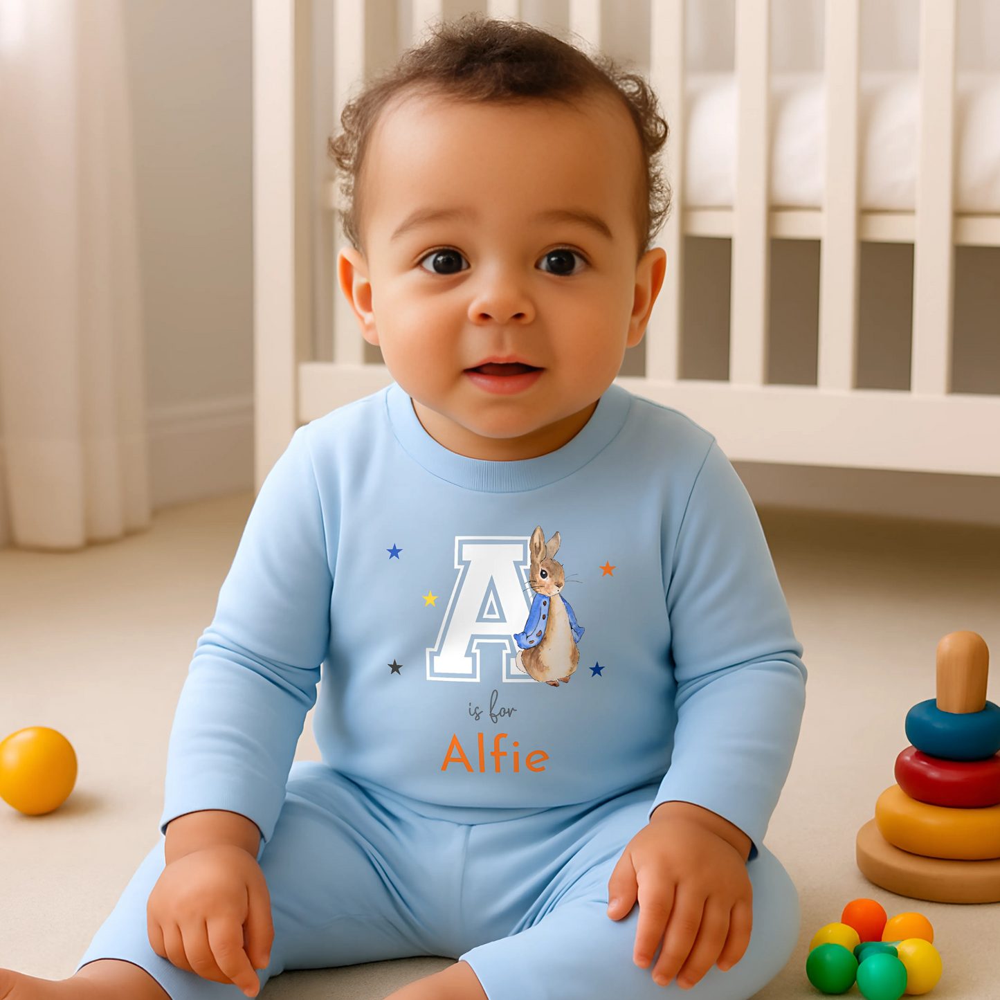 Personalised baby pyjamas: Blue Peter Rabbit-themed varsity-style pyjamas for baby boys, featuring a personalised initial and name. Designed for ages 0-2 years, this custom sleepwear set makes a thoughtful new baby gift. Ideal for personalised baby clothing, custom baby boys; clothes, and unique baby gifts.