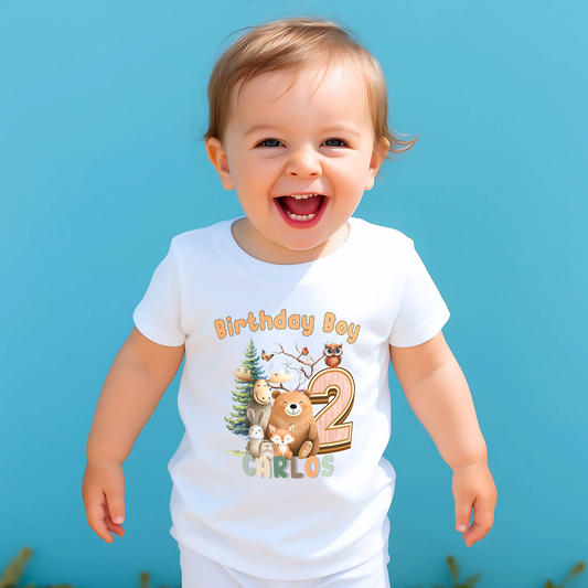 Woodland animal birthday t-shirt: A children's birthday t-shirt featuring a woodland animal theme. The shirt displays a forest scene with a playful fox, a curious bear, and a gentle bear, surrounded by lush greenery. The design uses earthy tones and vibrant greens to create a natural look. At the top, the words “Birthday Boy” are printed, with space for a personalized name underneath. Made from soft, high-quality fabric, it’s designed for comfort and durability.