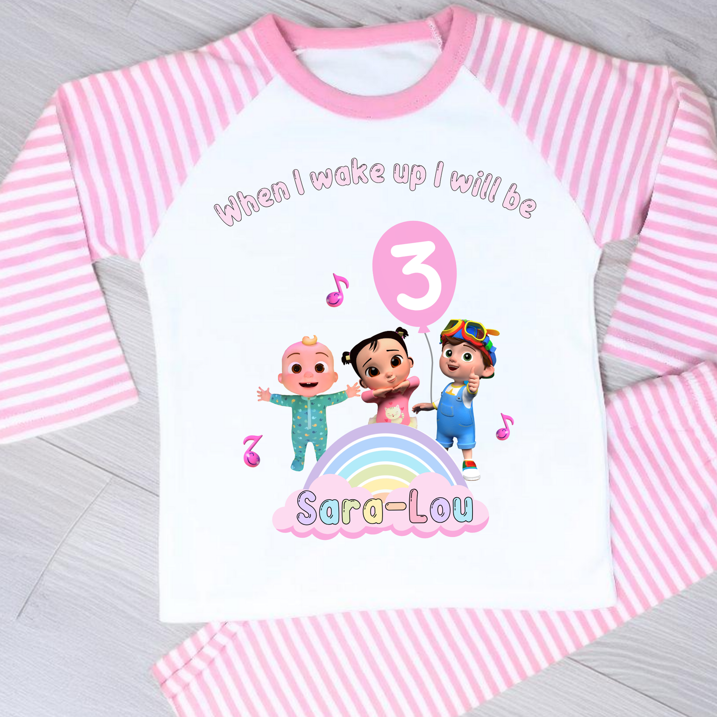 Cocomelon Birthday Pyjamas: Image of a set of Cocomelon Birthday Pyjamas for children, displayed on a soft, pastel-hued background. The pyjamas are made from a soft fabric and showcase a pastel rainbow color scheme, adorned with popular Cocomelon characters. The ensemble is designed to be both stylish and comfortable, making it perfect for birthday celebrations or a cosy night. The image emphasizes the playful and whimsical nature of the pyjamas, capturing the essence of fun for young fans of Cocomelon.