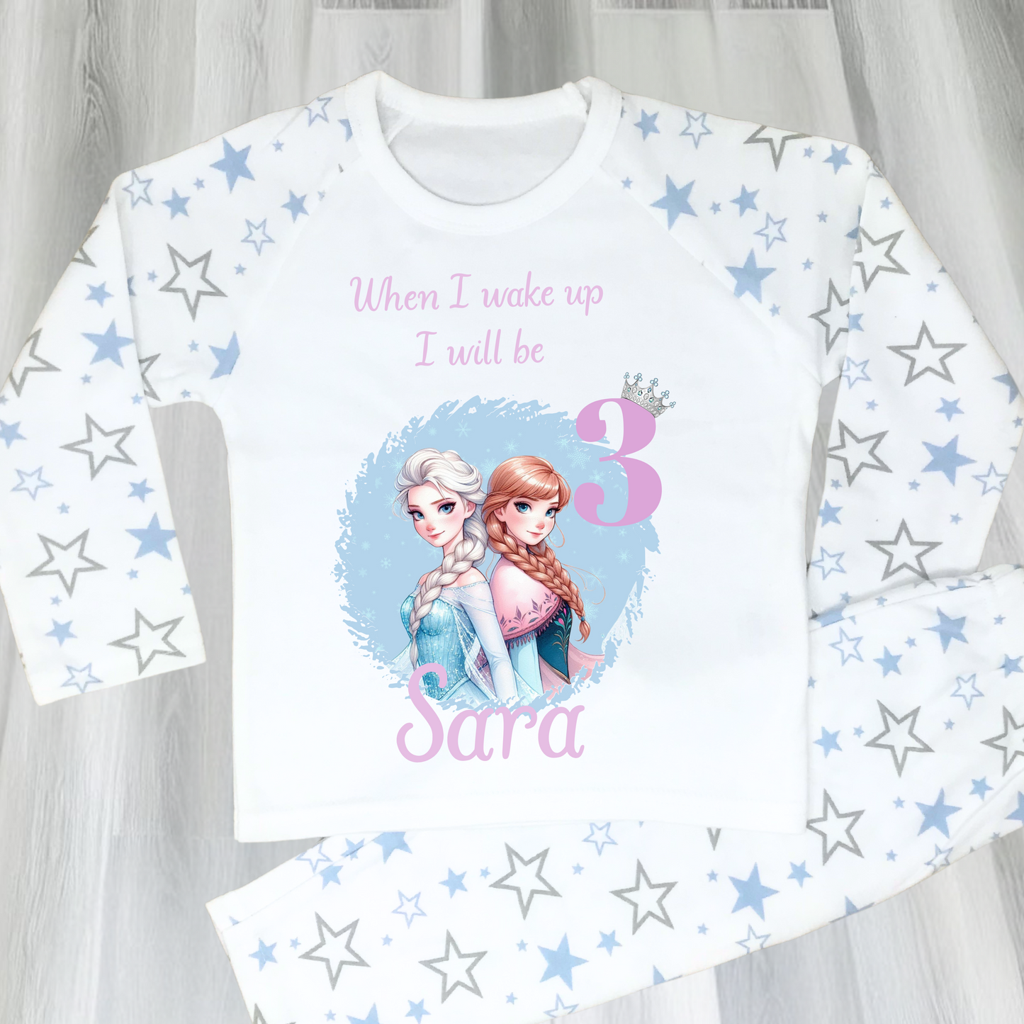 Personalised Frozen birthday pyjamas with name and age. Features Elsa and Anna in Frozen colours of blue and lilac. Perfect for birthday morning photos and celebrations.