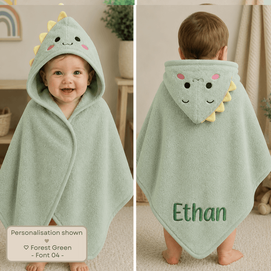 Personalised embroidered baby and toddler hooded towel with animal character hood, suitable from newborn to 3 years. A baby wearing a personalized forest green hooded towel wrap with a dinosaur face and yellow spikes, shown in a split front and back view. The name 'Ethan' is personalized on the back.
