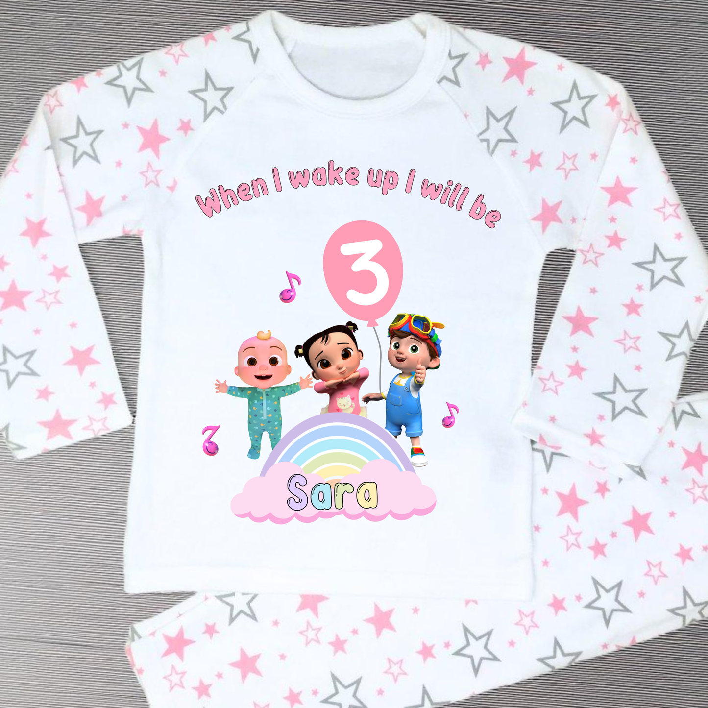 Cocomelon Birthday Pyjamas: Image of a set of Cocomelon Birthday Pyjamas for children, displayed on a soft, pastel-hued background. The pyjamas are made from a soft fabric and showcase a pastel rainbow color scheme, adorned with popular Cocomelon characters. The ensemble is designed to be both stylish and comfortable, making it perfect for birthday celebrations or a cosy night. The image emphasizes the playful and whimsical nature of the pyjamas, capturing the essence of fun for young fans of Cocomelon.
