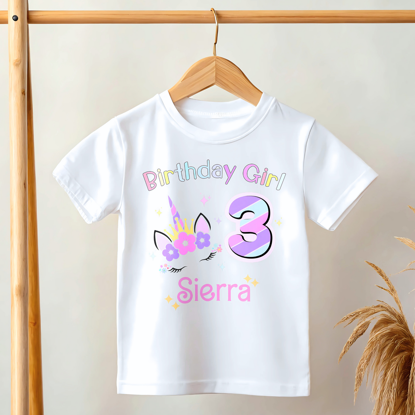 Unicorn Birthday T-shirt for girls, A personalised birthday t-shirt for girls, featuring a pink and purple unicorn design. The t-shirt is customisable with the child's name and age, making it a perfect birthday gift. The vibrant colours and whimsical unicorn imagery make it an ideal choice for a toddler celebrating her special day. The t-shirt is available in white, blue and pink.