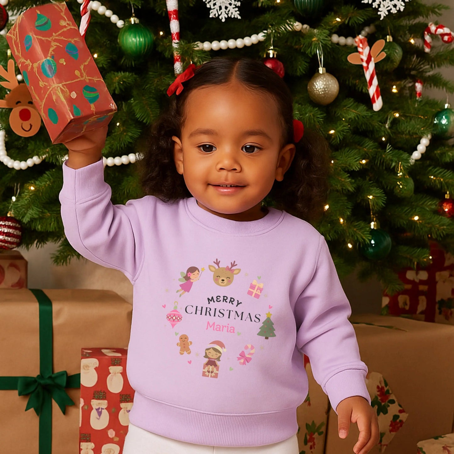 personalised christmas sweatshirt: Child wearing a pink personalised Christmas-themed sweatshirt with decorative elements on a light gray background.