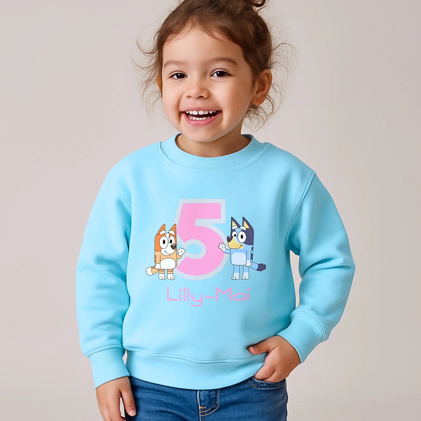 Persoalised Bluey and Bingo birthday sweatshirt: Child wearing a purple sweatshirt with bluey and bingo characters and her name underneath