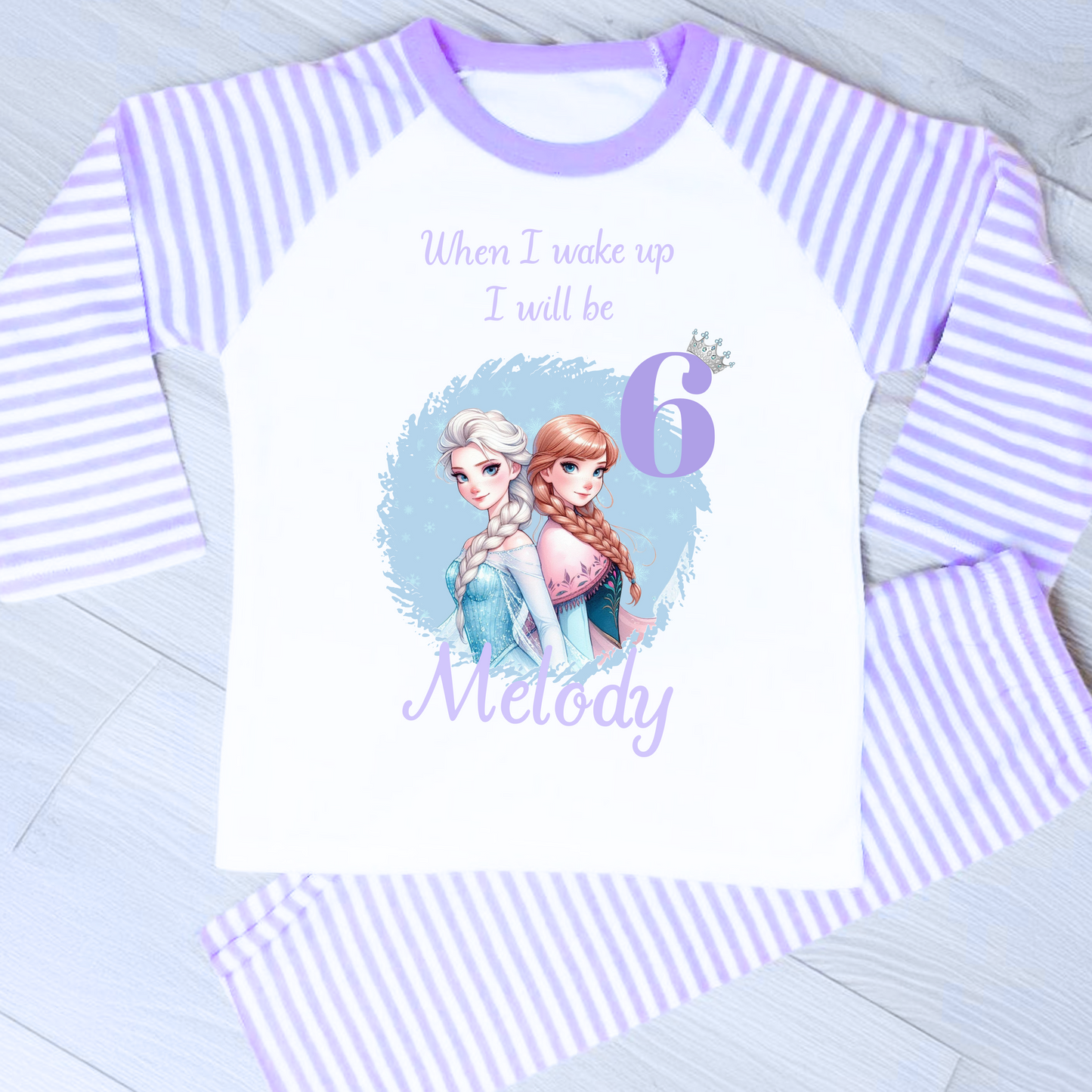 Personalised Frozen birthday pyjamas with name and age. Features Elsa and Anna in Frozen colours of blue and lilac. Perfect for birthday morning photos and celebrations.