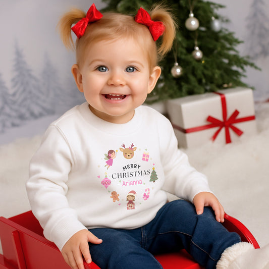 personalised christmas sweatshirt: Child wearing a pink personalised Christmas-themed sweatshirt with decorative elements on a light gray background.