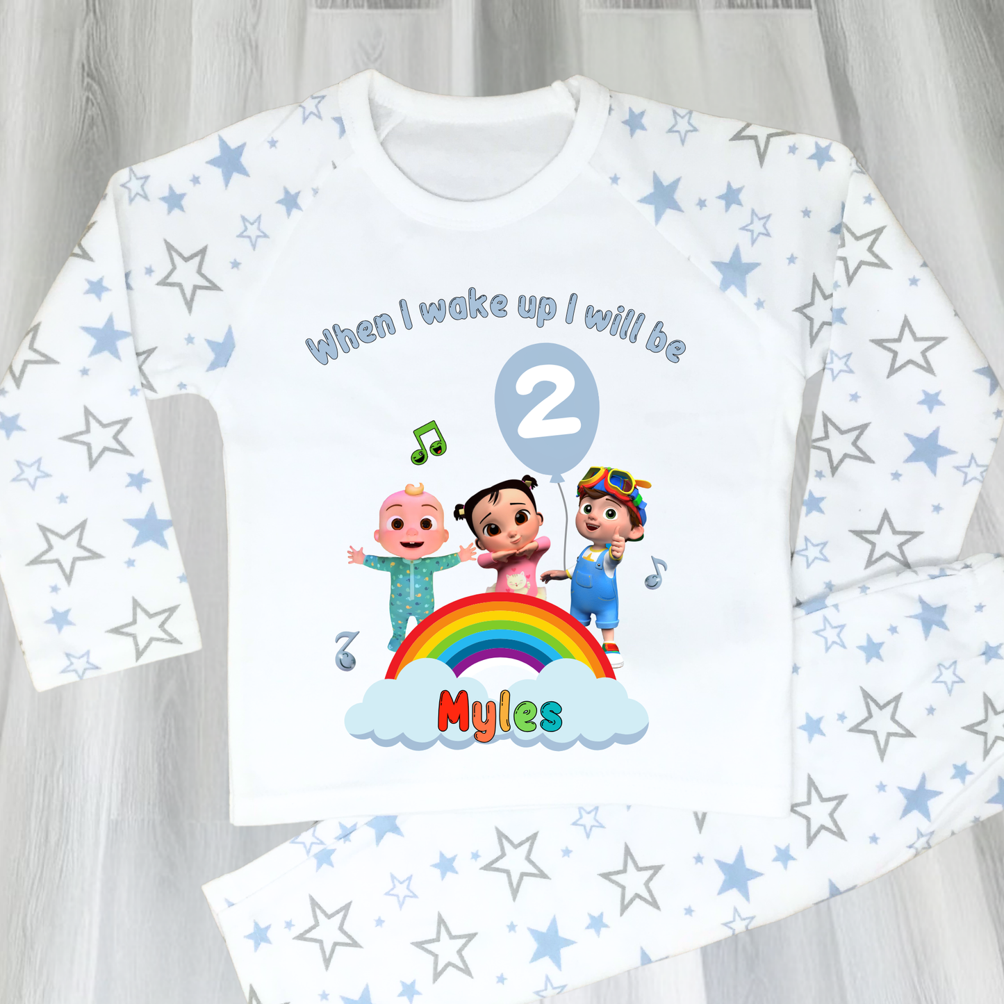 Cocomelon Birthday Pyjamas: Image of a set of Cocomelon Birthday Pyjamas for children, displayed on a soft, pastel-hued background. The pyjamas are made from a soft fabric and showcase a pastel rainbow color scheme, adorned with popular Cocomelon characters. The ensemble is designed to be both stylish and comfortable, making it perfect for birthday celebrations or a cosy night. The image emphasizes the playful and whimsical nature of the pyjamas, capturing the essence of fun for young fans of Cocomelon.
