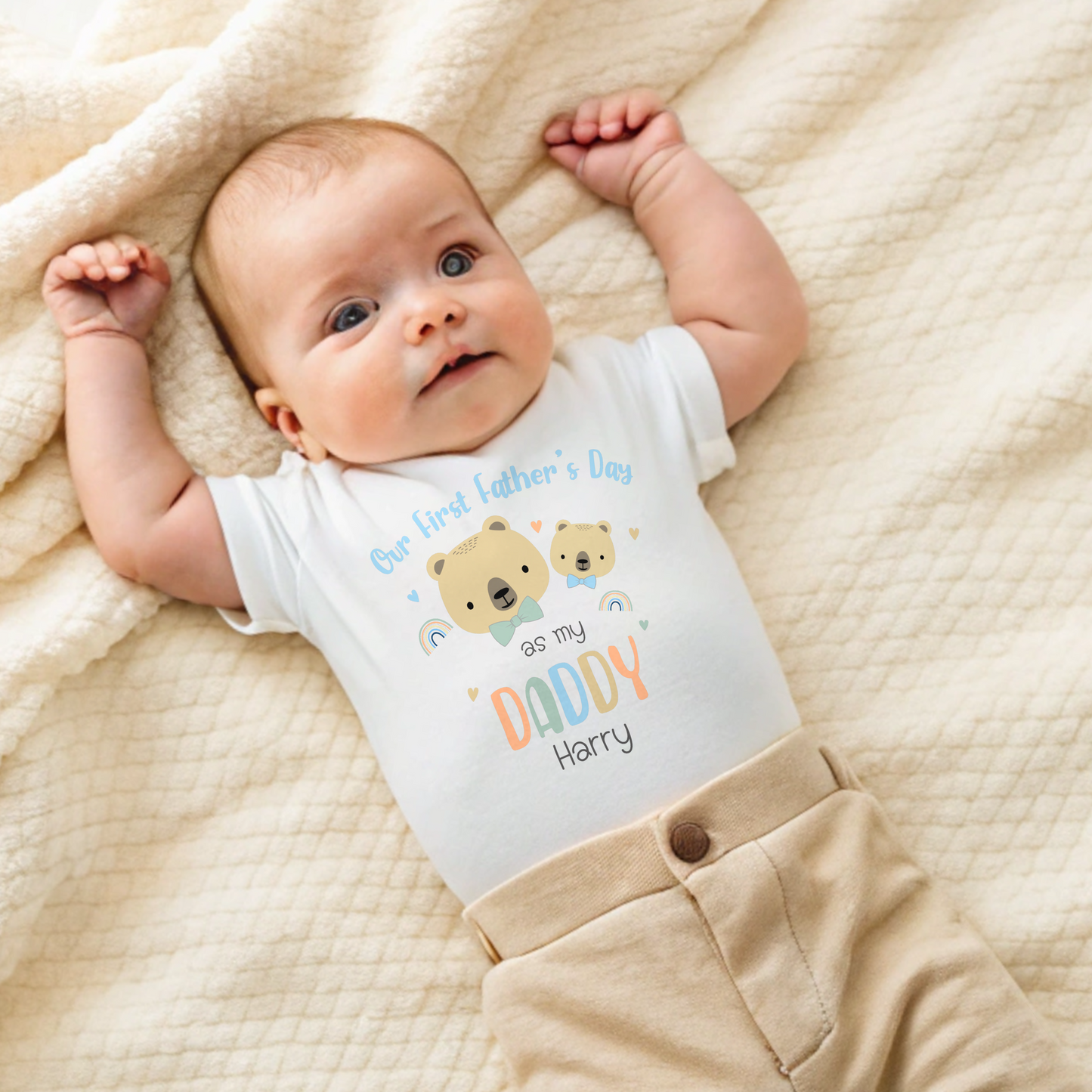 First Father's Day Outfit: A baby dressed in a personalized First Father’s Day outfit. This unique gift for new dads includes a choice of a sleepsuit, vest, T-shirt, or bib, all featuring a charming design. At the top, it reads “First Father’s Day as My Daddy,” accompanied by an adorable illustration of a baby bear and a father bear, along with the child’s name.