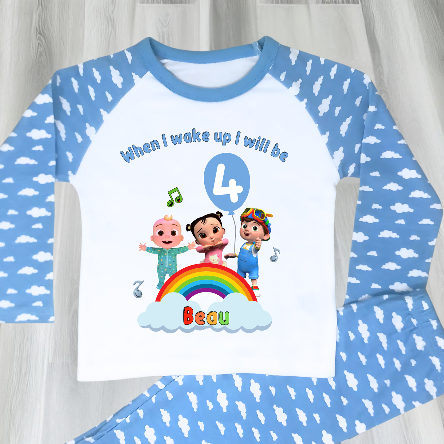 Cocomelon birthday pyjamas for boys with custom name and age, rainbow design with favourite Cocomelon characters, birthday number in blue balloon, and name printed under fluffy clouds, soft and comfy sleepwear set for birthday mornings