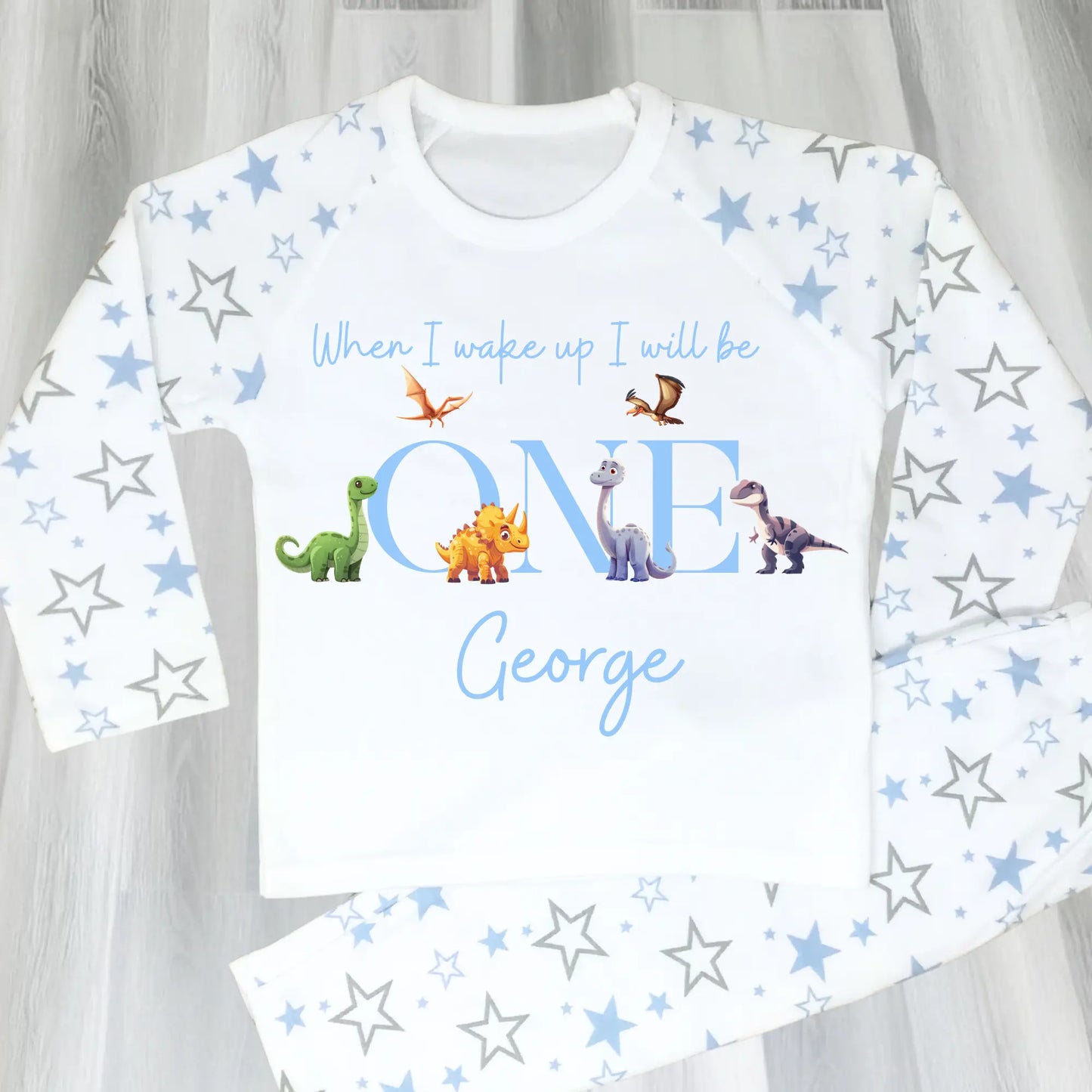 Dinosaur Birthday Pyjamas: A pair of toddler boys pyjamas with a dinosaur theme is displayed. The design features the phrase “When I Wake Up" accompanied by vibrant dinosaur graphics and the child's age. These two-piece pyjamas can be personalised with the boys name and age, creating a unique birthday outfit. Ideal for young dinosaur enthusiasts, these playful and colorful jammies make bedtime exciting and birthday mornings special.