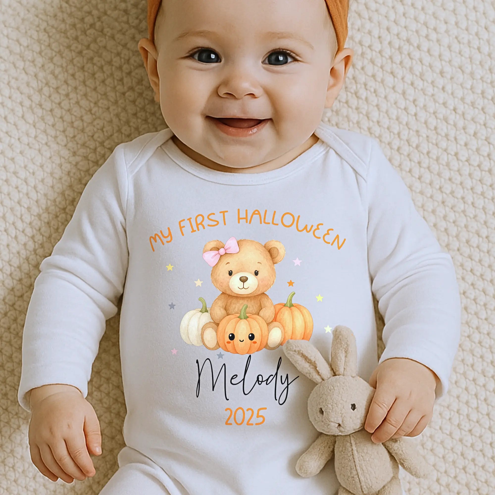Baby wearing a personalised first halloween outfit romper outfit with a teddy bear and pumpkins. On the top it reads My First Halloween with baby's name underneath and year.
