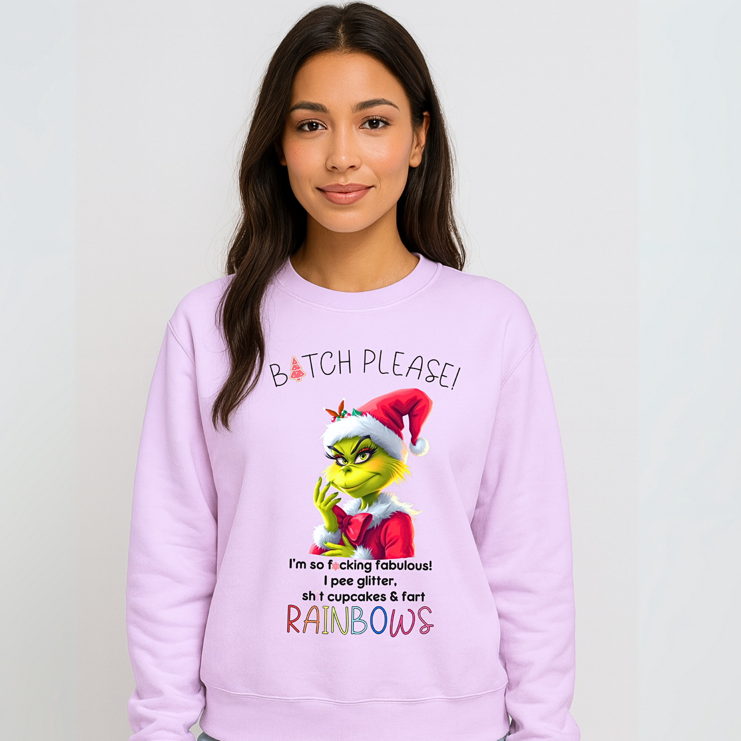Woman wearing a light purple Christmas sweatshirt featuring a cheeky Grinch design with Santa hat and funny festive quote in bold colourful text.