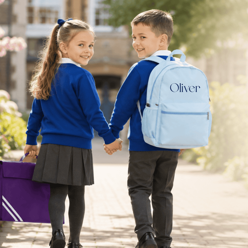 Personalised Kids School Essentials: Two children in UK school uniform walking hand in hand with a personalised blue backpack and personalised school book bag, representing our personalised Back to School collection.