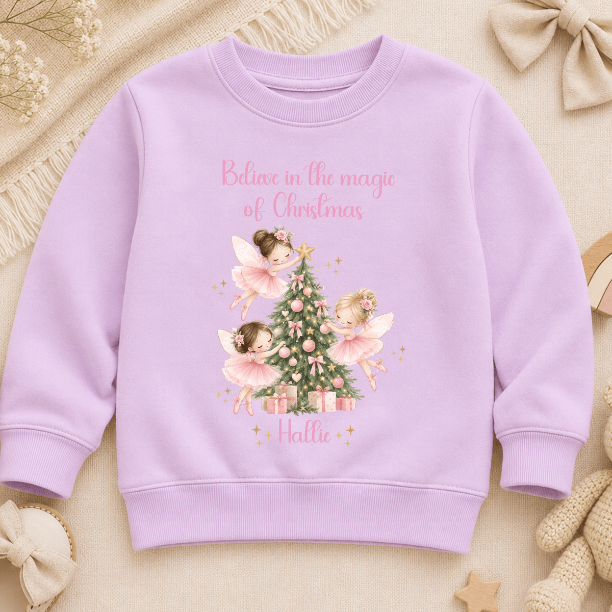 Personalised Christmas sweatshirt for girls featuring magical pink fairies decorating a Christmas tree, customised with the child’s name.