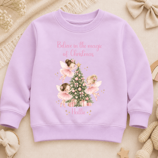 Personalised Christmas sweatshirt for girls featuring magical pink fairies decorating a Christmas tree, customised with the child’s name.