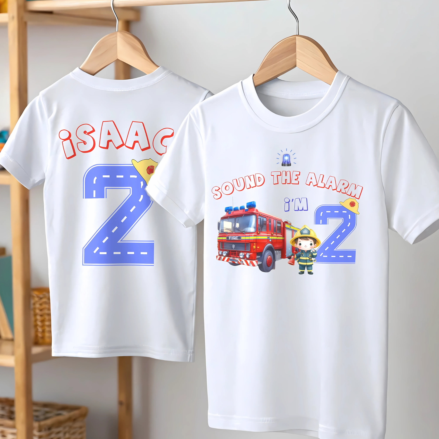 Personalised Fire Engine Birthday T-Shirt: A customizable white birthday shirt featuring a red fire truck and firefighter. The top reads “Sound the Alarm I'm” followed by your choice of age number. The back displays the toddler's name and a blue number adorned with a firefighter hat. An ideal gift for firefighter-themed birthday parties for toddlers.