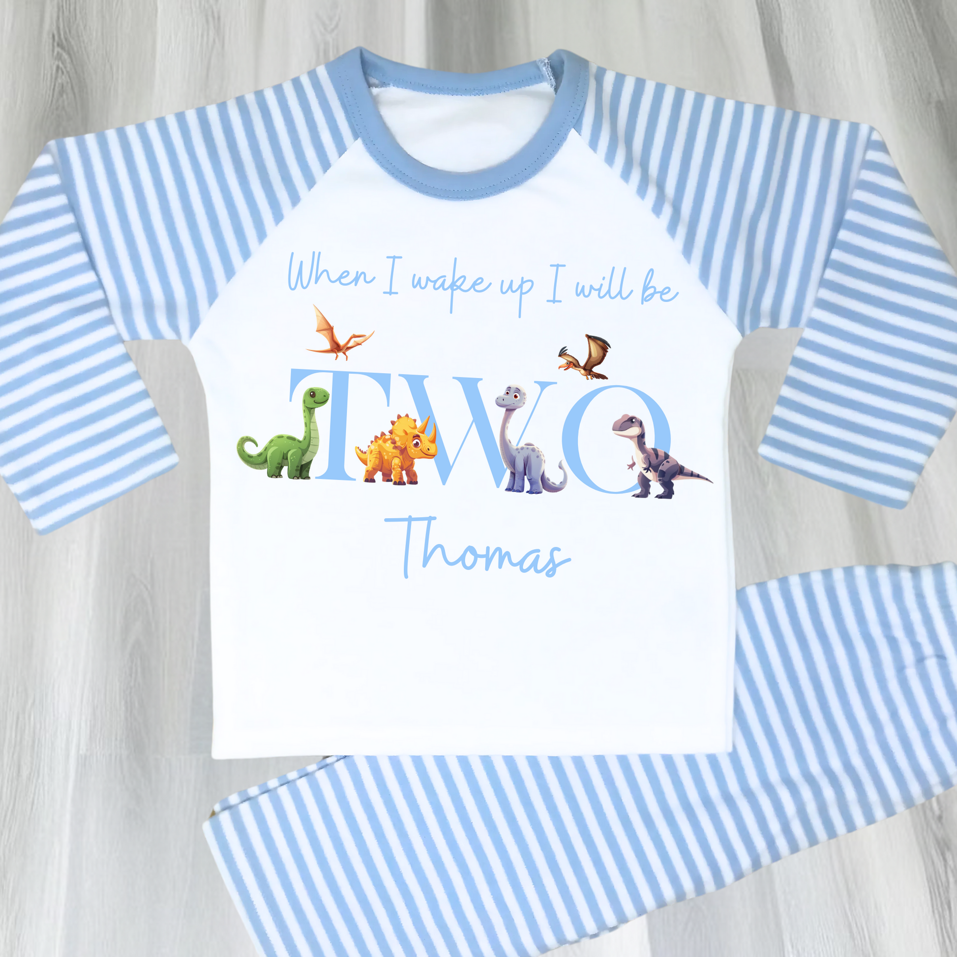 Dinosaur Birthday Pyjamas: A pair of toddler boys pyjamas with a dinosaur theme is displayed. The design features the phrase “When I Wake Up" accompanied by vibrant dinosaur graphics and the child's age. These two-piece pyjamas can be personalised with the boys name and age, creating a unique birthday outfit. Ideal for young dinosaur enthusiasts, these playful and colorful jammies make bedtime exciting and birthday mornings special.