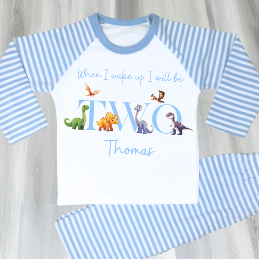 Dinosaur Birthday Pyjamas: A pair of toddler boys pyjamas with a dinosaur theme is displayed. The design features the phrase “When I Wake Up" accompanied by vibrant dinosaur graphics and the child's age. These two-piece pyjamas can be personalised with the boys name and age, creating a unique birthday outfit. Ideal for young dinosaur enthusiasts, these playful and colorful jammies make bedtime exciting and birthday mornings special.