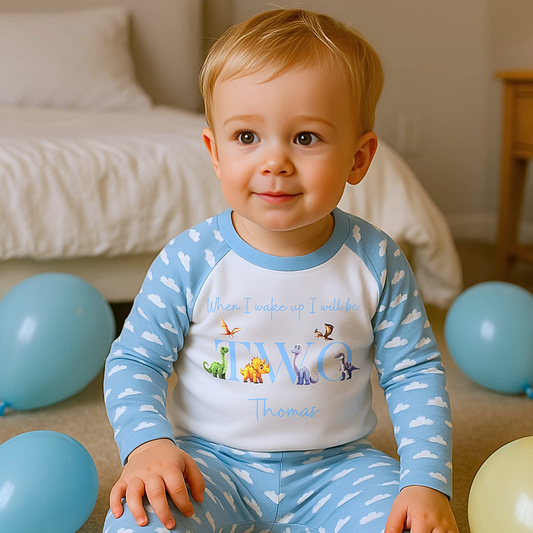Dinosaur Birthday Pyjamas: A pair of toddler boys pyjamas with a dinosaur theme is displayed. The design features the phrase “When I Wake Up" accompanied by vibrant dinosaur graphics and the child's age. These two-piece pyjamas can be personalised with the boys name and age, creating a unique birthday outfit. Ideal for young dinosaur enthusiasts, these playful and colorful jammies make bedtime exciting and birthday mornings special.