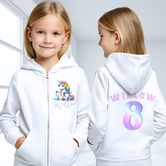 girls unicorn hoodie: A personalised girl's zip-up hoodie featuring a colourful unicorn graphic on the front, along with the girl's initial and name. The back showcases her name and favourite number. Perfect for a unicorn-themed birthday celebration! Custom girls hoodie, unicorn graphic jacket, personalised name and number hoodie, unicorn-themed apparel, birthday hoodie for girls.