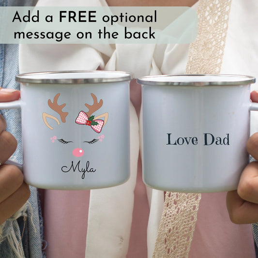 Kids Christmas mug: Two personalised Christmas mugs held by hands, one with a reindeer design and name 'Myla', the other with 'Love Dad' text. Xmas gift for girls and kids.
