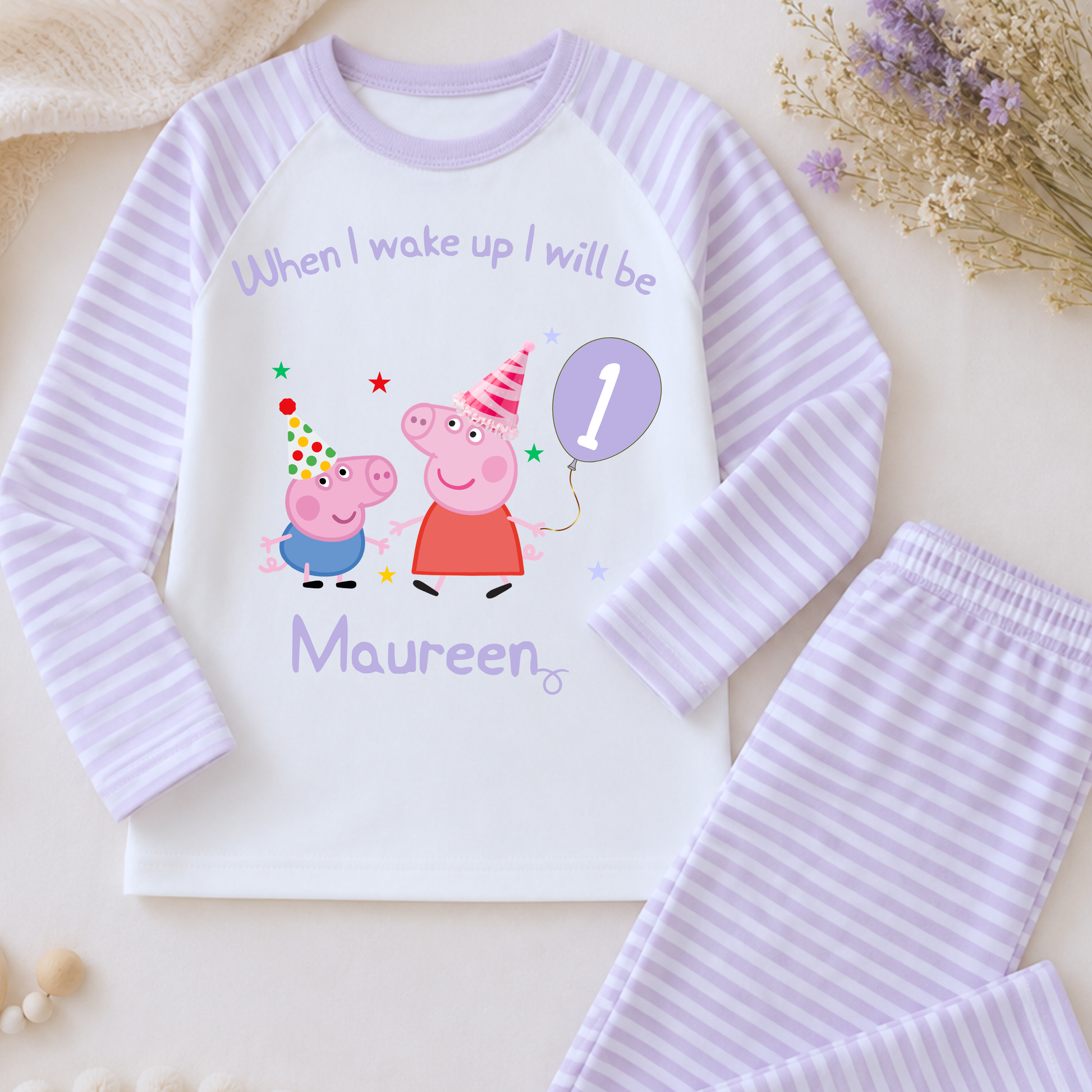 Girls Personalised Peppa and George Pig Birthday Pyjamas, Peppa Pig Personalised Pyjamas, When I wake Up I'll Be Pj's, Girls Peppa Pig Pjs, Peppa Pig Birthday Gift, Name Pyjamas, Happy Birthday Pjs, A children's two-piece pajama set laid flat on a light beige surface, featuring a white long-sleeve top with lavender striped sleeves and collar, a colorful Peppa Pig birthday graphic with the text 'When I woke up I will be Maureen', and matching lavender-and-white striped pants.