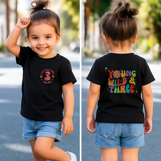Young Wild and three birthday t-shirt: A girls' birthday T-shirt with a "Young Wild and Three" theme, showcasing a groovy retro style. The front features whimsical retro emojis and the words "birthday girl" alongside a customisable name on the left breast. The back displays bold retro fonts and graphics for a nostalgic touch. Made from soft, high-quality fabric, this vibrant and playful tee is designed for comfort and style, perfect for third birthdays.