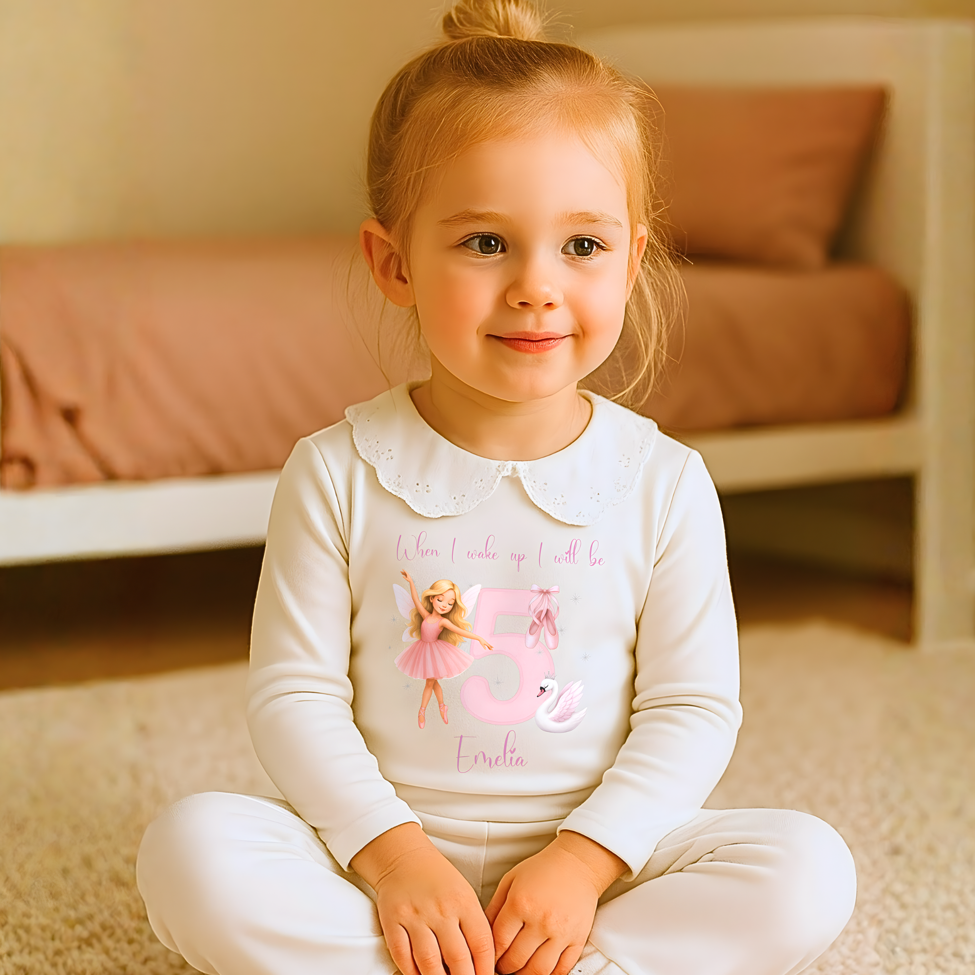 Young girl wearing a white outfit with a fairy design and text, sitting on a carpeted floor.