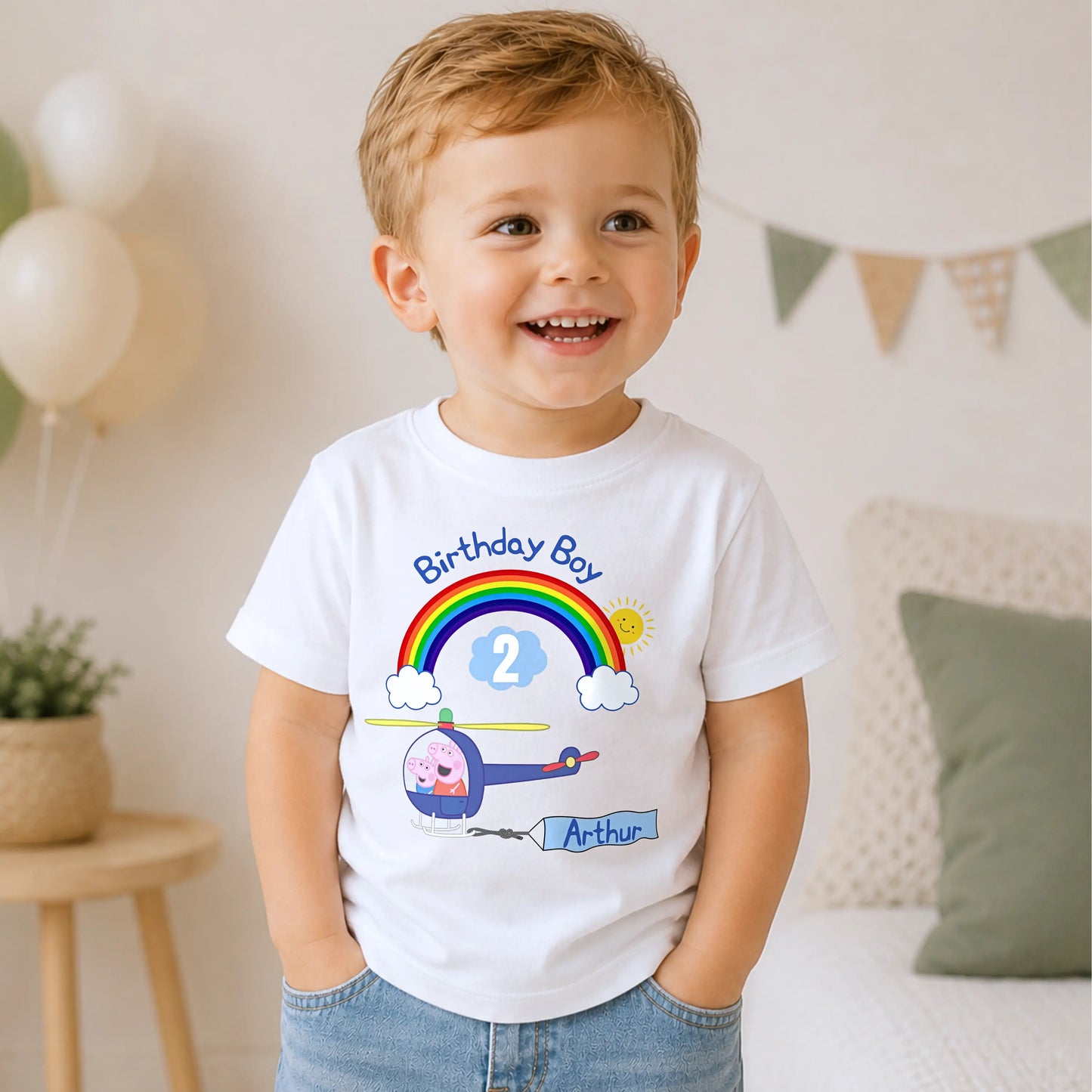 A smiling young boy wearing a white t-shirt with Personalised Peppa Pig and George birthday T-shirt for boys featuring a helicopter, rainbow, custom name Arthur and age 2 birthday design.
