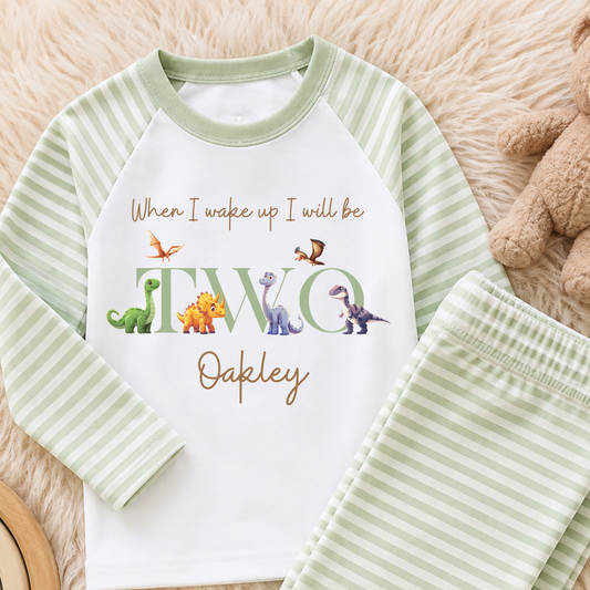 Personalised Boys Dinosaur Birthday Pyjamas with child's name and age, featuring colourful dinosaurs, long-sleeve top and coordinating striped bottoms.
