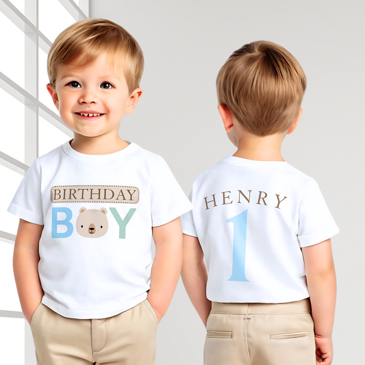 Teddy Bear Birthday T-shirt, Personalized Brown Bear Birthday T-Shirt: A charming white t-shirt showcasing a neutral theme with an adorable teddy bear head graphic and the words “Birthday Boy” in eye-catching beige, blue, and sage tones. The back is personalized with the child's name and age, making it the perfect birthday gift or celebration outfit for a toddler boy, ideal for memorable birthday photos and parties.