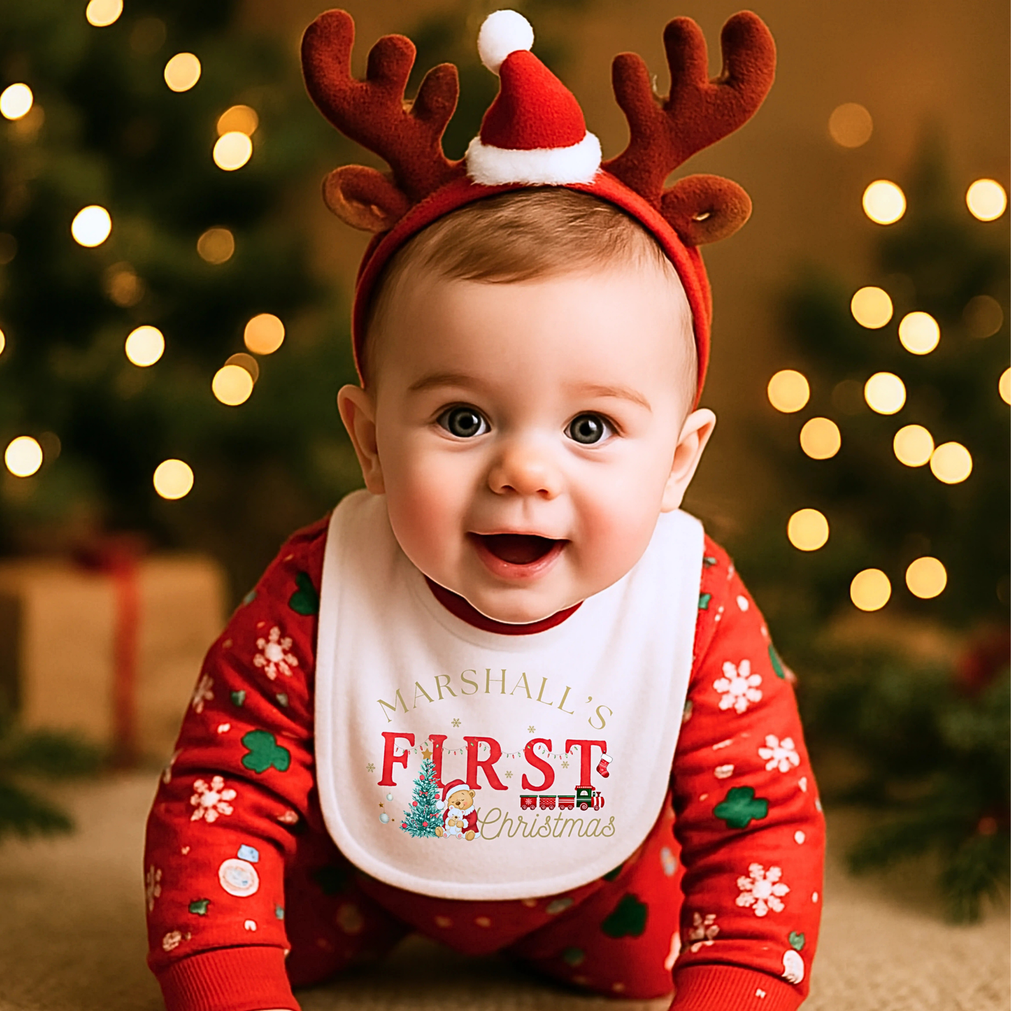 First Chrstmas Outfit, Baby wearing a red outfit with reindeer antlers and a bib, standing in front of Christmas lights and decorations.