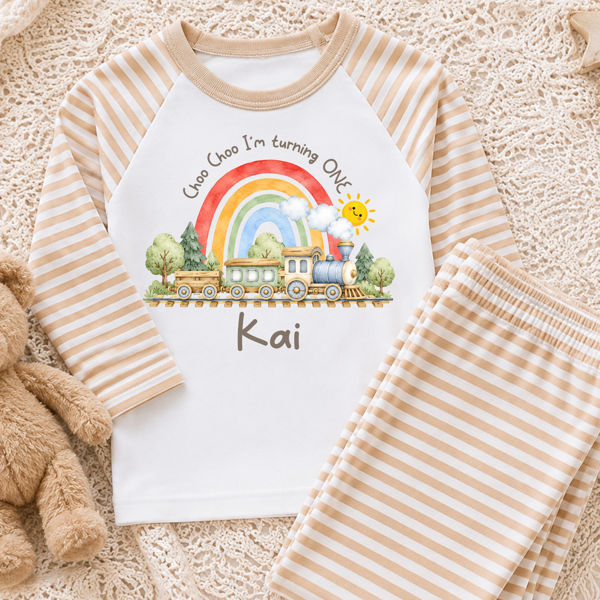 Personalised Train Birthday Two-Piece Set with watercolour steam train, rainbow, smiling sun and child's name. Available in sage green, beige and baby blue stripes.