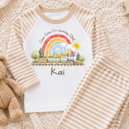 Personalised Train Birthday Two-Piece Set with watercolour steam train, rainbow, smiling sun and child's name. Available in sage green, beige and baby blue stripes.