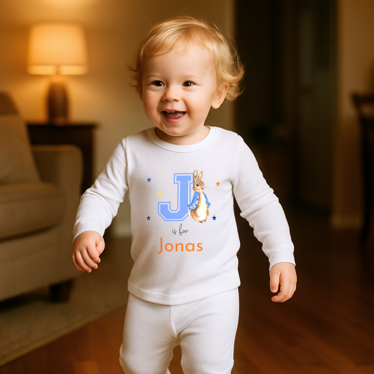 Personalised baby pyjamas: Blue Peter Rabbit-themed varsity-style pyjamas for baby boys, featuring a personalised initial and name. Designed for ages 0-2 years, this custom sleepwear set makes a thoughtful new baby gift. Ideal for personalised baby clothing, custom baby boys; clothes, and unique baby gifts.