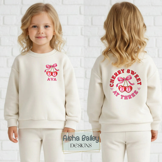 Personalised birthday loungewear set for girls with cherry and bow design, custom name and age print, soft sweatshirt and matching bottoms for birthday celebrations