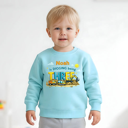 Digger birthdaysweatshirt personalised with child’s name and age, featuring colourful construction vehicles on a kids birthday jumper