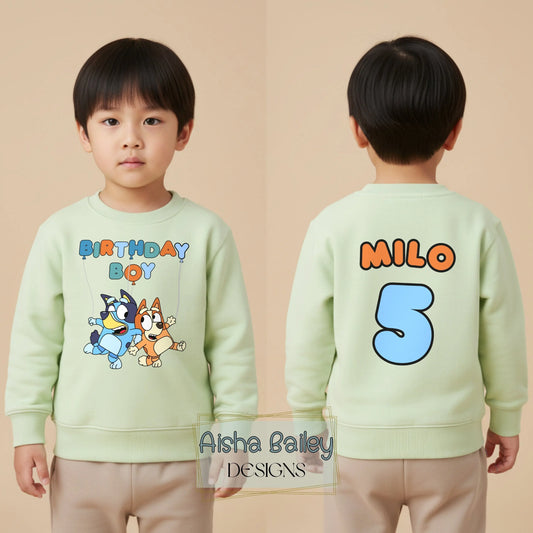 Personalised Bluey birthday boy sweatshirt for toddlers featuring a fun “Birthday Boy” design with Bluey characters on the front, and custom name “Tommy” with a large number 3 printed on the back. Made from soft, high-quality fabric for all-day comfort, this custom kids birthday outfit is perfect for parties, photos, and everyday wear. Ideal personalised Bluey jumper for boys, combining cute character style with a unique name and age design.
