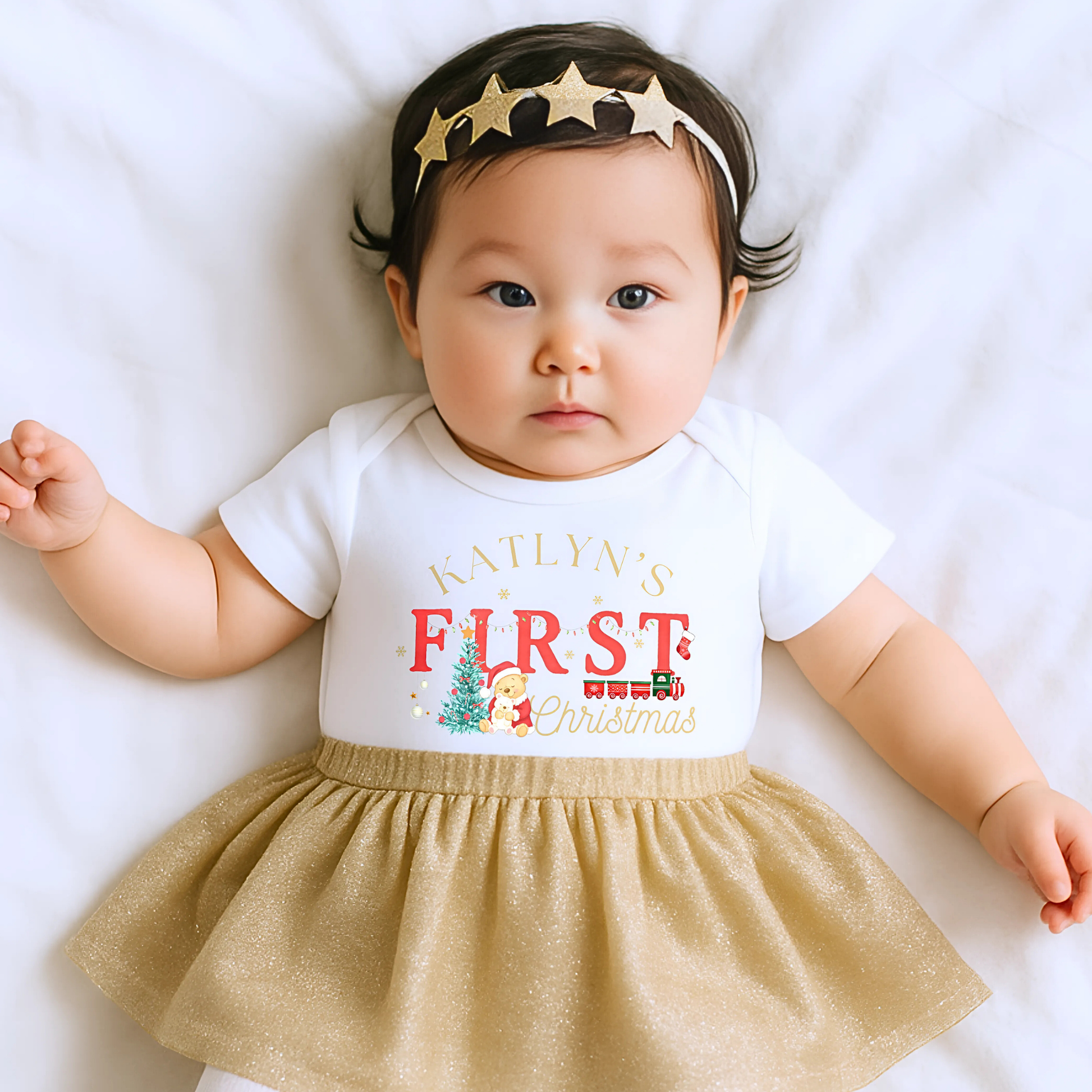 First Chrstmas Outfit, Baby wearing a personalised First Christmas outfit with a gold skirt and star headband on a white background.