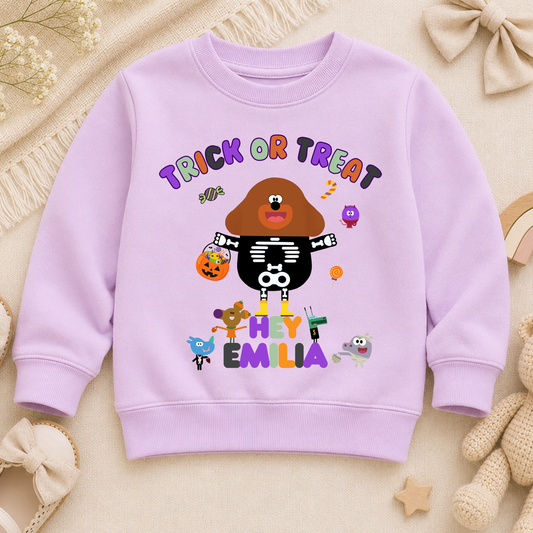 Flat lay of a personalised Halloween sweatshirt with trick-or-treat hey Duggee design and custom name
