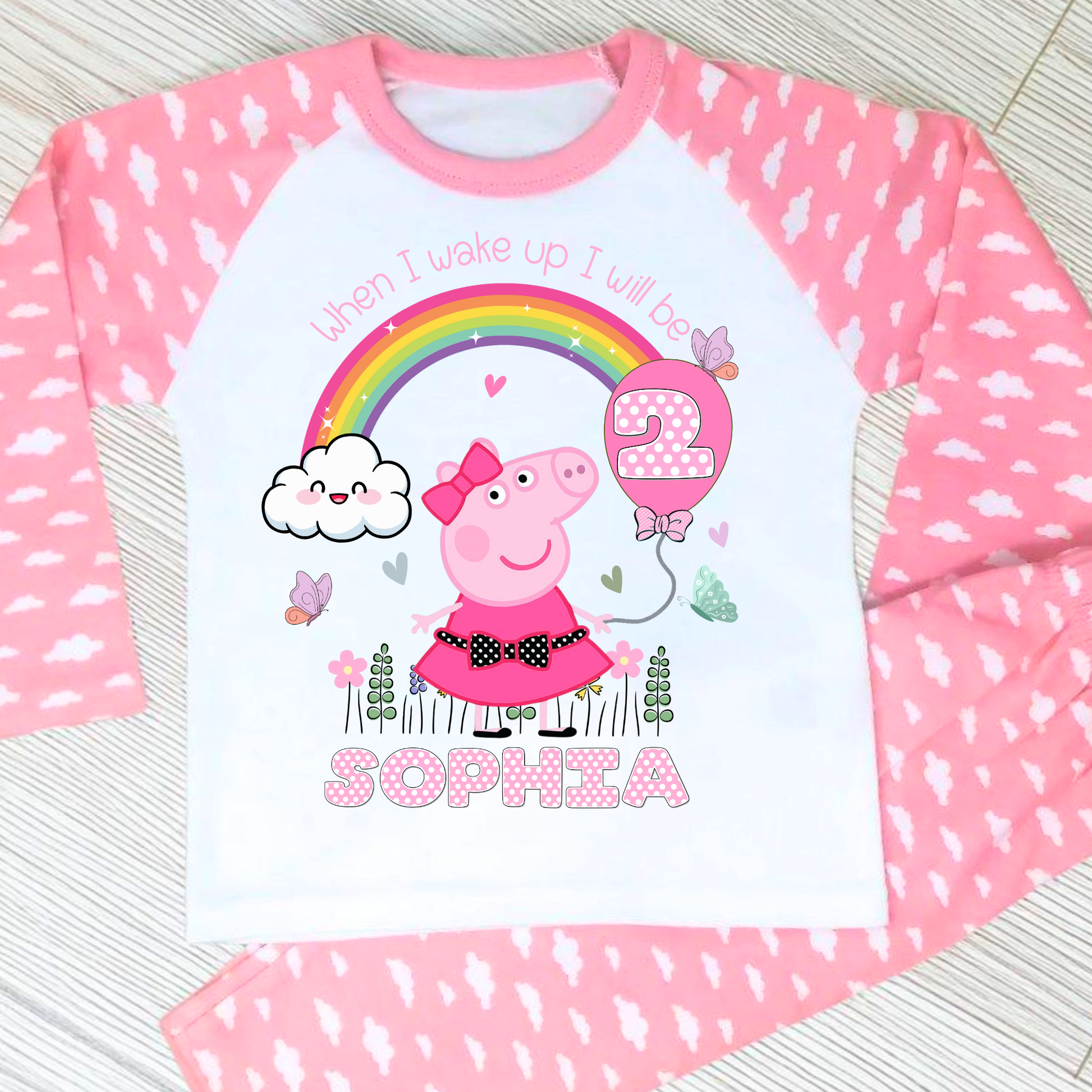 Peppa Pig birthday pyjamas: set of Personalised Peppa Pig Birthday Pyjamas designed for little girls, featuring Peppa Pig in a whimsical spring garden theme with blooming flowers and vibrant colours. The pyjamas include a playful rainbow with pink polka dots, displaying the child's age for a personalised touch. The set is personalised with the child's name, making it a unique gift for Peppa Pig fans, perfect for wearing on the eve of their birthday.