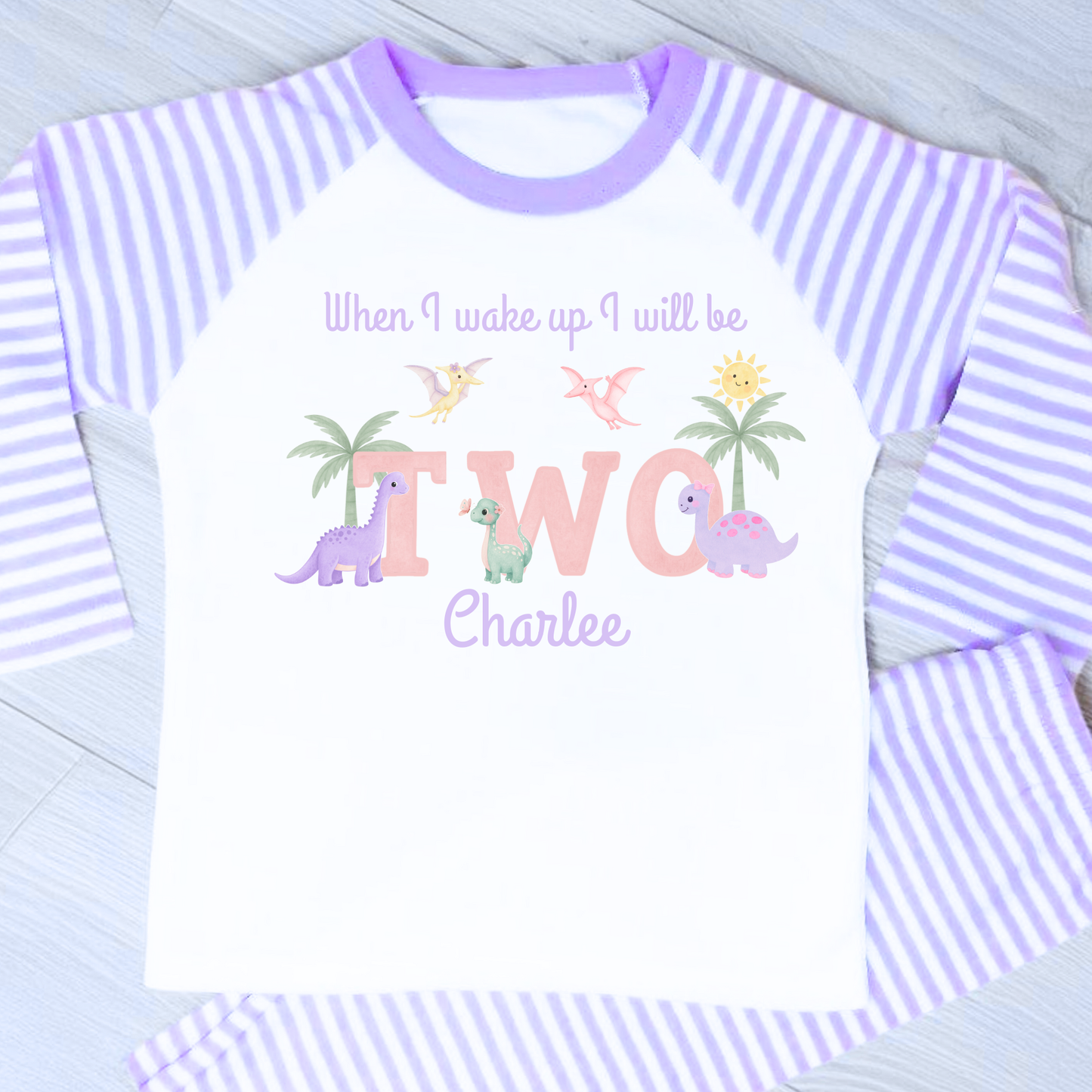 Girls dinosaur birthday pyjamas personalised with name and age featuring pastel dinosaurs and palm trees with custom name